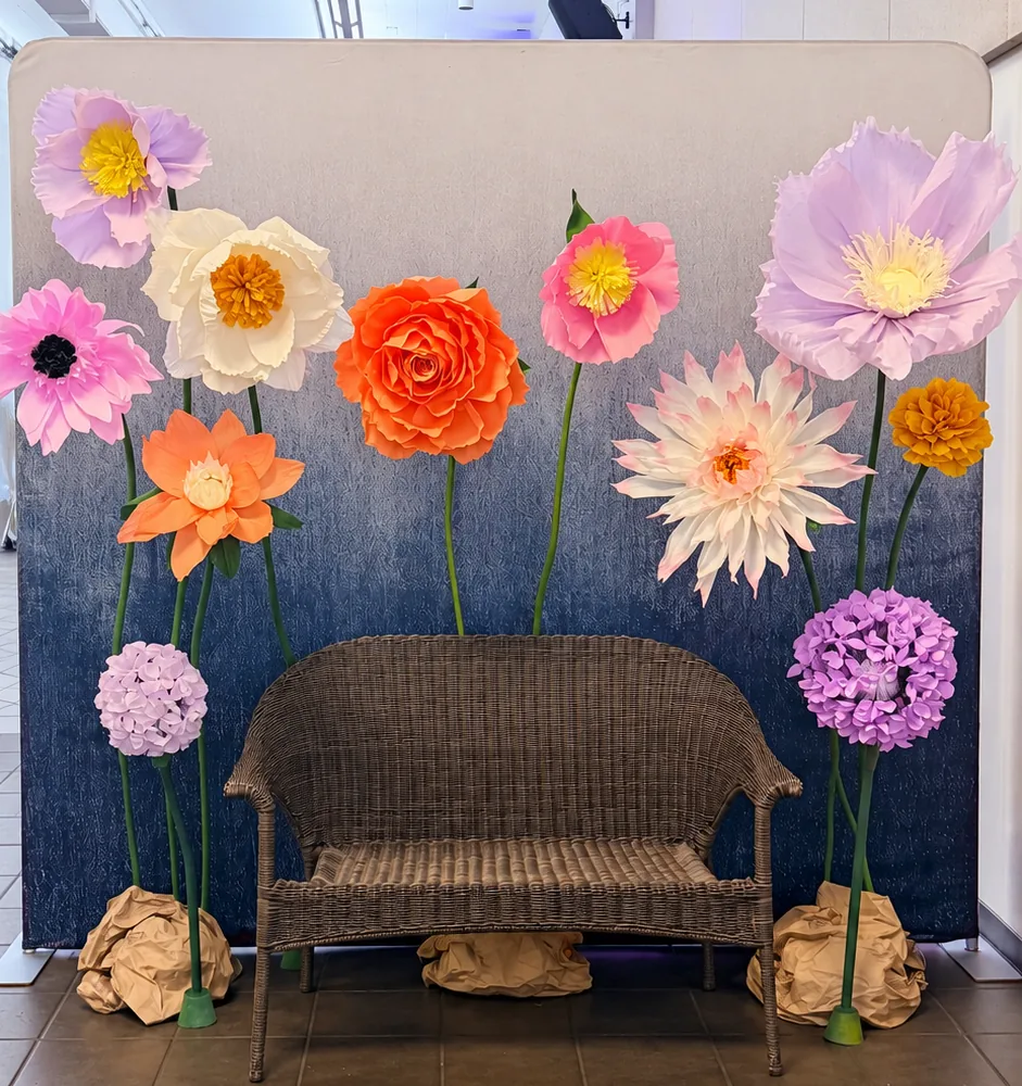 Giant paper flower wall with a wicker bench